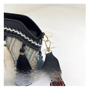 Detail of bohemian bucket bag with colorful woven strap, blue tassels, and gold hardware