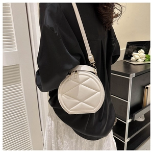 Macro shot of white quilted round crossbody bag with geometric texture and gold zippers