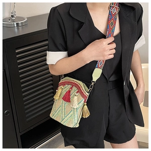 Detailed close-up of ethnic woven bucket bag with colorful tassels and patterned strap