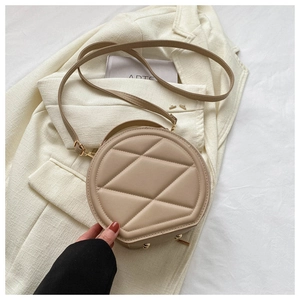 Detail of round beige crossbody bag with quilted diamond pattern and gold zipper hardware