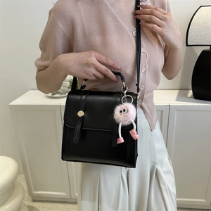 Sac à main noir structuré polyvalent avec charme en peluche rose et bandoulière réglable