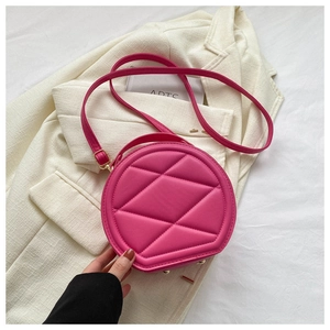 Close-up of rose red circular bag showing quilted geometric patterns and gold metal buckle