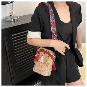 Detail of bohemian woven bucket bag featuring vibrant multi-colored tassels and patterned strap