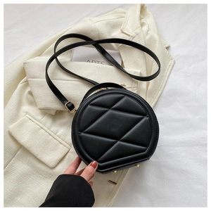 Detail of black round crossbody bag with geometric quilting and gold metal hardware