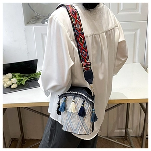Detail of bohemian woven bucket bag featuring blue tassels and ethnic geometric strap