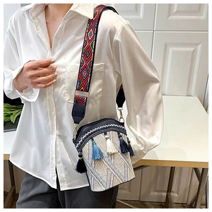 Close-up of woven bucket bag with vibrant ethnic style tassel and embroidered strap