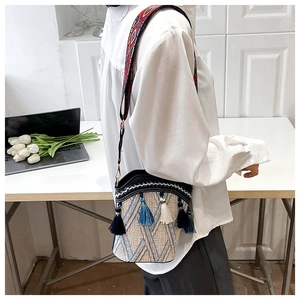 Detailed side view of an ethnic woven bucket bag with blue tassels and a colorful strap