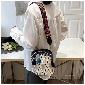 Detail view of ethnic bucket bag with bohemian tassels and colorful jacquard strap