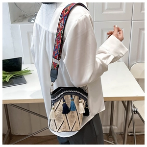 Detailed shot of ethnic straw bucket bag featuring colorful tassels and woven strap