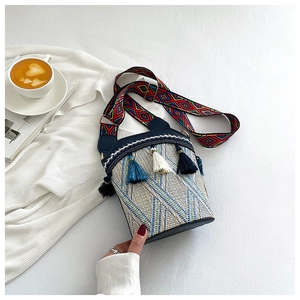 Close-up of bohemian woven bucket bag with colorful tassels and geometric strap