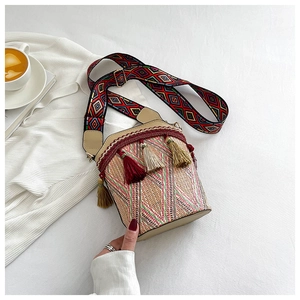 Detailed close-up of straw bucket bag with vibrant tassels and ethnic woven strap