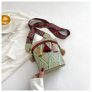 Detailed top view of ethnic woven bucket bag with tassels and colorful geometric strap