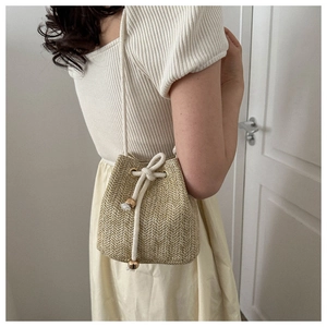 Detailed weave pattern on woven bucket bag with white drawstring and gold beads