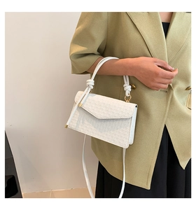 Witte gewatteerde crossbodytas met knoopdetail aan het handvat bij moderne outfit