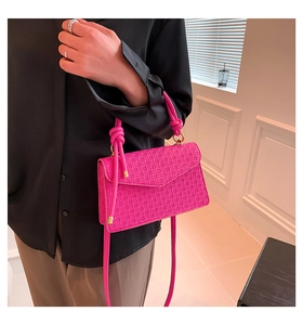 Detail van roze handtas met reliëf voorzien van elegante knoopgreep en schouderband