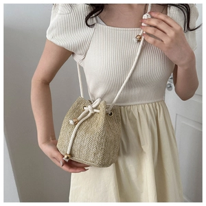 Detail of hand-woven straw bucket bag with cotton drawstring closure and gold hardware