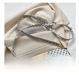 Detail of printed crossbody bag featuring golden buckle and adjustable shoulder strap