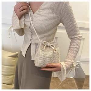 Close-up of woven straw bucket bag with drawstring closure and fine woven texture