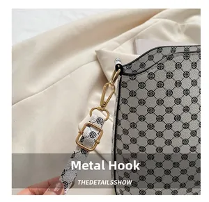 Macro detail of polished gold metal hook and buckle on a floral pattern crossbody bag