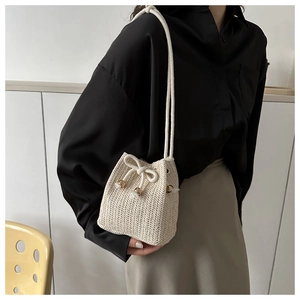 Detail of hand-woven ivory bucket bag featuring V-shaped texture and drawstring closure