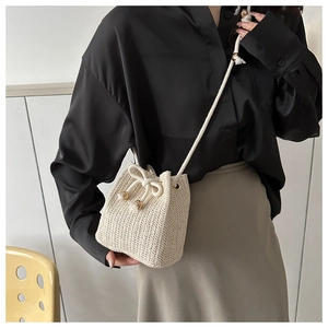 Detail of hand-woven cream bucket bag featuring drawstring closure and bow decoration