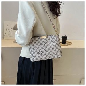 Detail of vintage patterned crossbody bag showing beige print and gold metal buckles