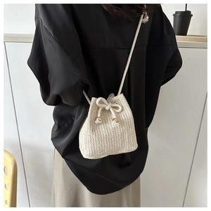 Detail of woven straw bucket bag with drawstring closure and elegant fringe accents