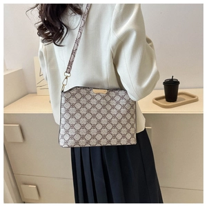 Detail of vintage patterned crossbody bag with metallic gold buckle and textured strap