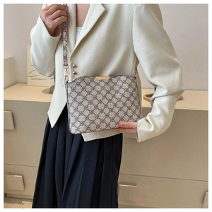 Detail of vintage patterned crossbody bag with gold metal trim on white blazer