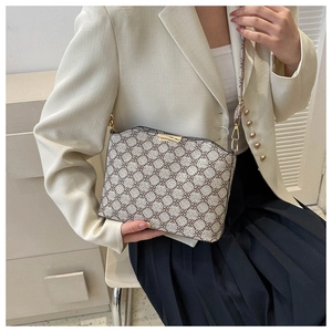 Detail of vintage beige floral crossbody bag with gold buckle on model in ivory blazer