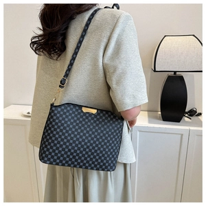 Detail of a black crossbody bag with blue dot pattern and golden metal hardware details