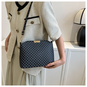 Detail of blue geometric pattern crossbody bag with gold metal trim worn by a model