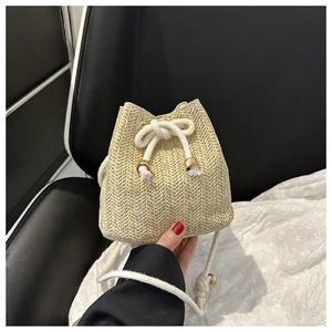 Detail of woven straw bucket bag with cotton drawstring closure and gold metal tips