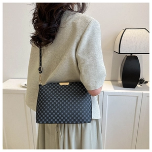Detail of crossbody bag with black polka dot pattern and gold metal hardware on model