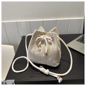 Detail of cream woven bucket bag with herringbone texture and white cotton drawstring