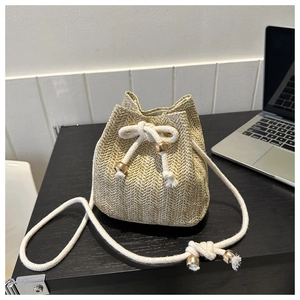 Detail of hand-woven straw bucket bag with cotton drawstring and gold bead accents