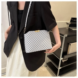 Detail view of white monogram crossbody bag with black geometric pattern and gold hardware