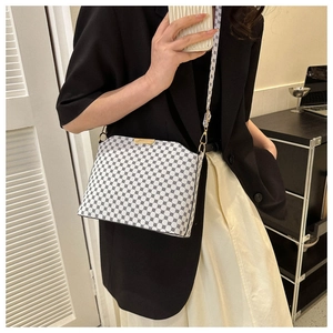 Detail of white leather crossbody bag featuring black geometric patterns and gold hardware