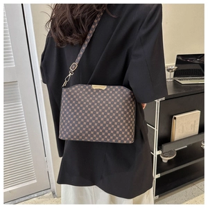 Woman in black blazer wearing vintage brown monogram crossbody bag in a modern office setting