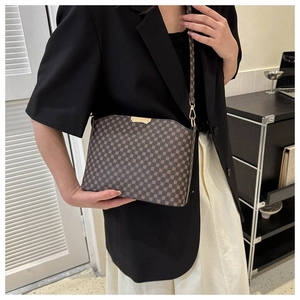 Detail of brown monogram crossbody bag with gold hardware worn by model in suit
