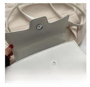 Close-up of silver magnetic clasp on white lychee grain leather crossbody bag