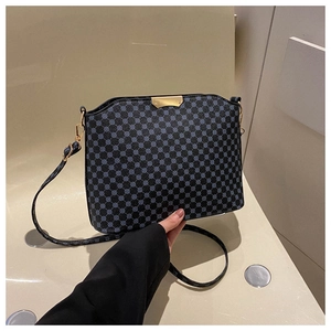 Detail showing the retro blue polka dot pattern and golden hardware on the black crossbody bag