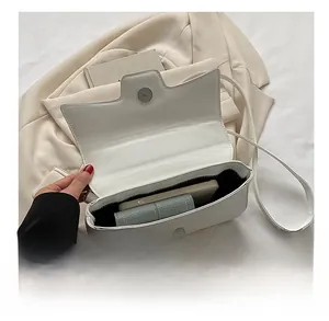 Detail showing internal capacity of the white leather crossbody bag with a smartphone and wallet