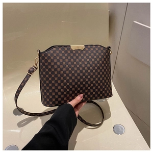 Detail view of a brown monogram square crossbody bag with gold metal plate and thin strap