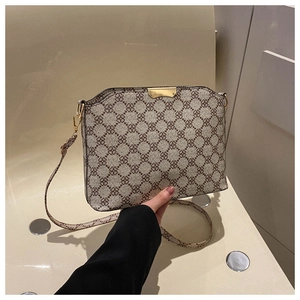 Detail view of monogram patterns and gold hardware on an elegant cream handbag