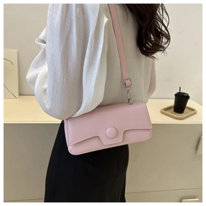 Close-up of a light pink minimalist shoulder bag worn by a model in a stylish interior
