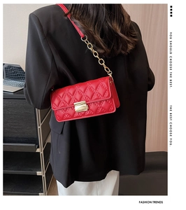 Detail of red quilted crossbody bag featuring a gold clasp and chain strap on a model