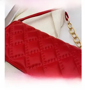 Macro shot of red quilted faux leather texture with elegant gold chain strap detail