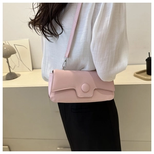 Detail of light pink crossbody bag showing geometric flap design and circular buckle
