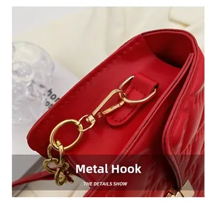 Detailed close-up of the golden metal hook and red quilted leather of the handbag